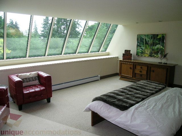 Spacious bedroom with large windows, red leather chair, and modern decor. - 455 Keith Road, West Vancouver