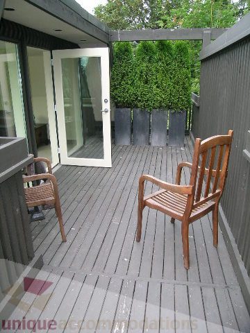 Furnished patio with wooden chairs and privacy hedge. - 455 Keith Road, West Vancouver