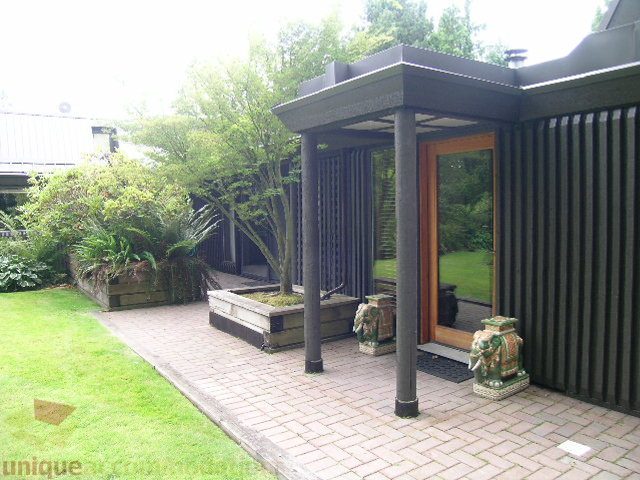 Furnished patio with modern design, black columns, and greenery. - 455 Keith Road, West Vancouver
