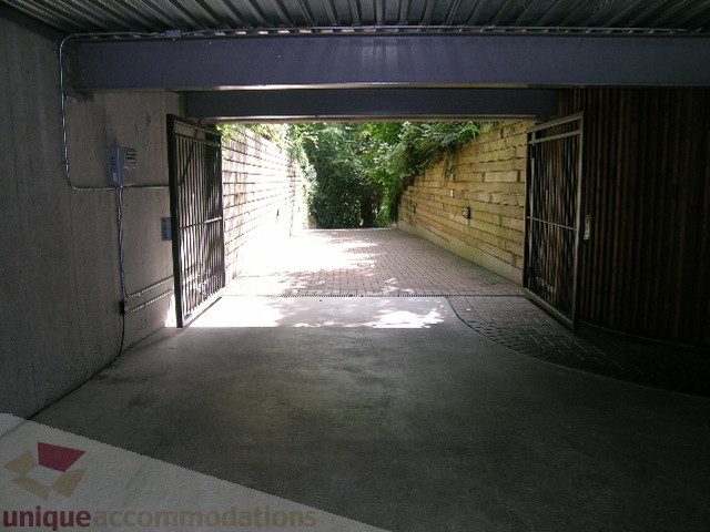 Fenced entrance to a private courtyard with brick walls and greenery. - 455 Keith Road, West Vancouver