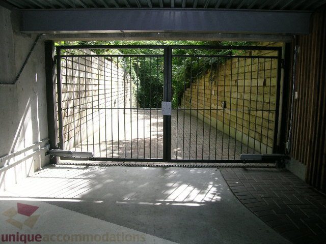 Fenced patio with brick flooring and greenery in background. - 455 Keith Road, West Vancouver
