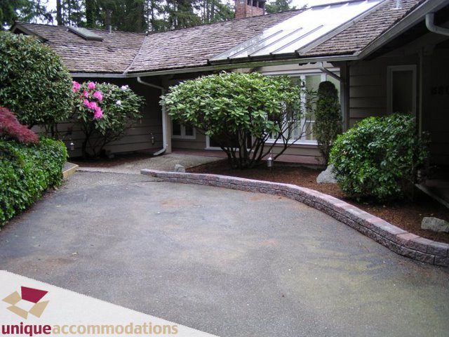 Bright patio with stone accents and lush greenery. - 3580 Westmount Court, West Vancouver