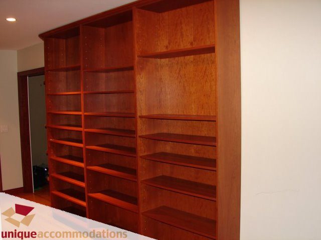 Furnished living room with built-in wooden shelves and hardwood floors. - 3580 Westmount Court, West Vancouver