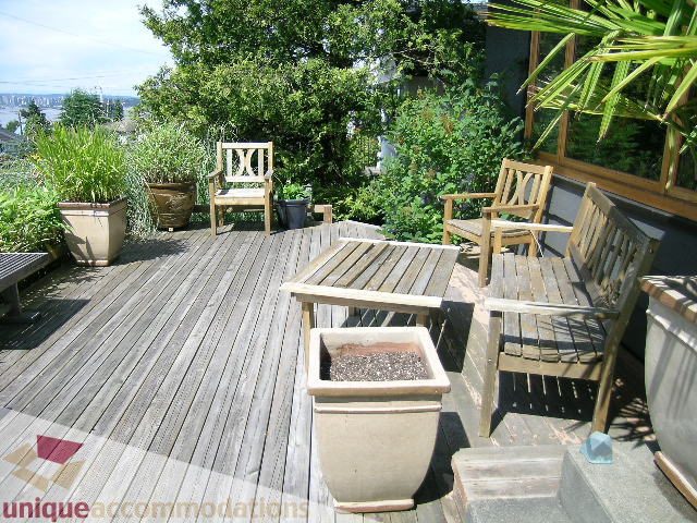 Furnished outdoor patio with wooden furniture and potted plants, overlooking a scenic view. - 408 E 7th Street, North Vancouver