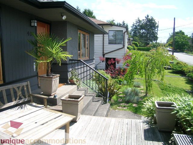 Furnished deck with wooden flooring, potted plants, and a view of the garden. - 408 E 7th Street, North Vancouver