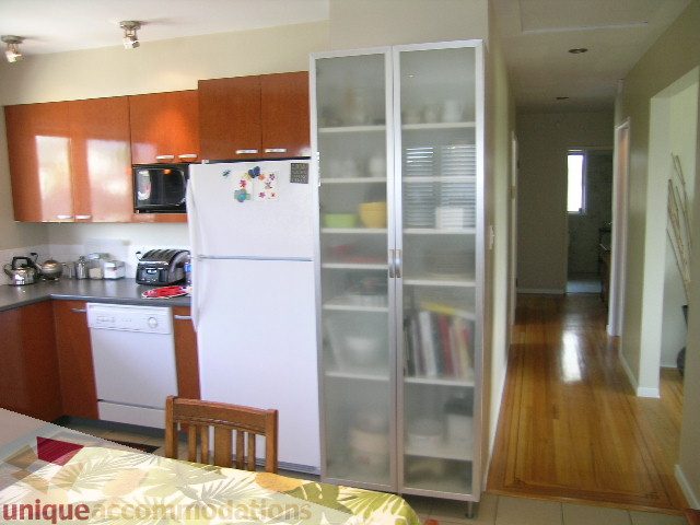 Bright kitchen with white appliances, wooden cabinets, and hardwood floors. - 408 E 7th Street, North Vancouver