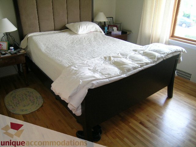 Furnished bedroom with hardwood floors and a large bed, neatly made. - 408 E 7th Street, North Vancouver