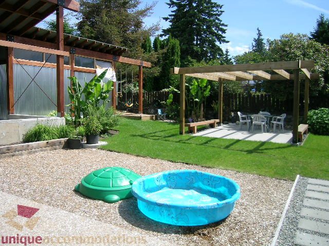 Fenced backyard with swing set, sandbox, and kiddie pool. - 408 E 7th Street, North Vancouver
