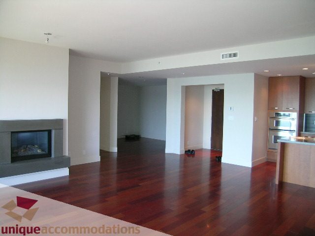 Open-concept living area with hardwood floors and a modern fireplace. - 1302 - 3355 Cypress Pl, West Vancouver