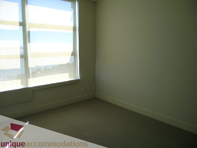 Bright bedroom with large window, city view, and carpeted floor. - 1302 - 3355 Cypress Pl, West Vancouver