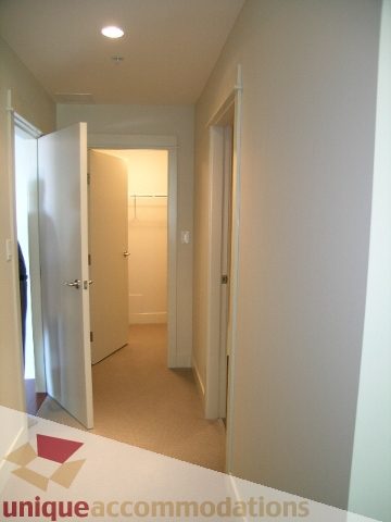 Bright hallway with open door leading to another room, neutral tones, clean lines. - 1302 - 3355 Cypress Pl, West Vancouver