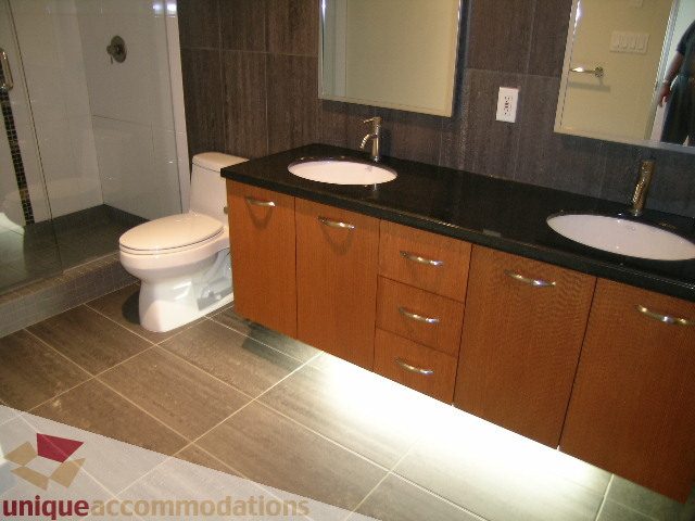 Modern bathroom with dark countertops and wooden cabinets. - 1302 - 3355 Cypress Pl, West Vancouver