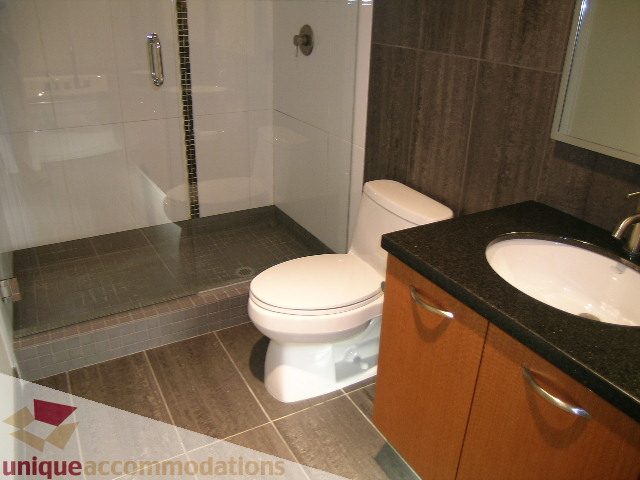 Furnished bathroom with dark countertops and wooden cabinets. - 1302 - 3355 Cypress Pl, West Vancouver