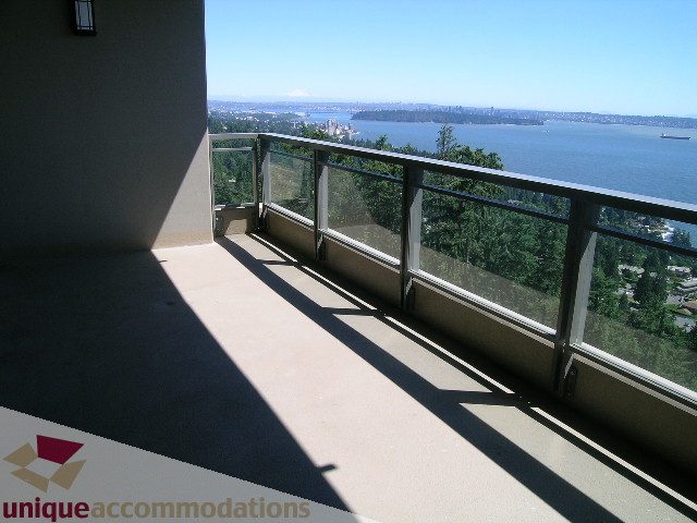 Spacious balcony with glass railings, offering stunning views of the water and greenery. - 1302 - 3355 Cypress Pl, West Vancouver