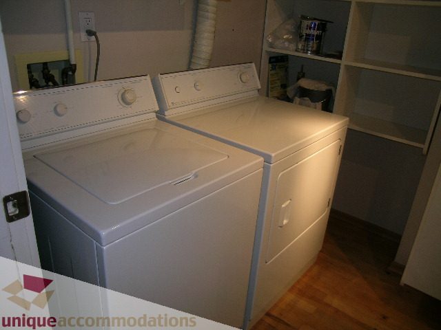 Bright laundry room with white washer and dryer, hardwood floors. - 402-1155 Mainland St, Vancouver Downtown