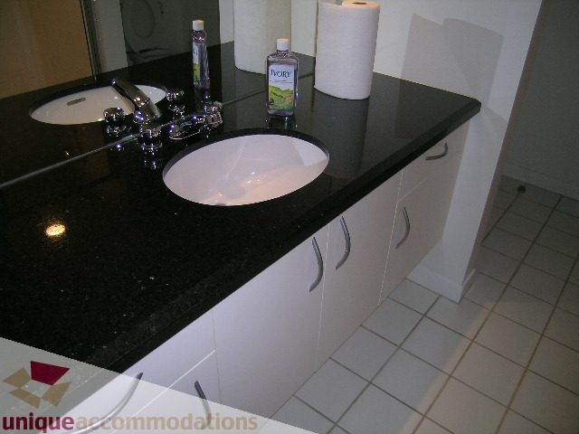 Bathroom with black granite countertops and white cabinets. - 402-1155 Mainland St, Vancouver Downtown