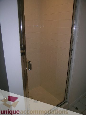 Shower with beige tiles and glass door. - 402-1155 Mainland St, Vancouver Downtown
