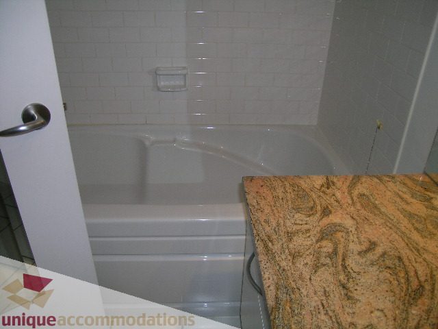 Bathroom with granite countertops and white tiled walls. - 402-1155 Mainland St, Vancouver Downtown