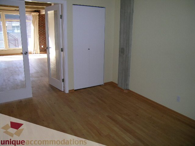 Bright living room with hardwood floors and a view of the kitchen. - 402-1155 Mainland St, Vancouver Downtown