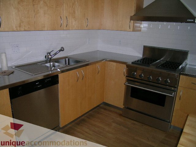 Bright kitchen with stainless steel appliances, hardwood floors, and a modern design. - 402-1155 Mainland St, Vancouver Downtown