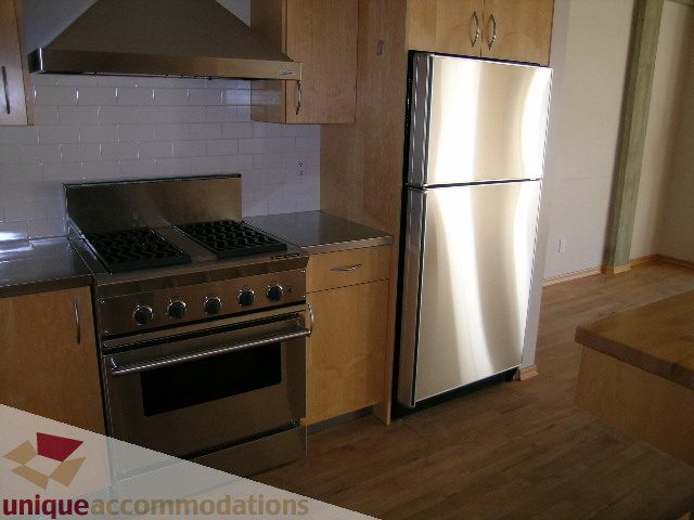 Bright kitchen with stainless steel appliances, hardwood floors, and modern cabinetry. - 402-1155 Mainland St, Vancouver Downtown
