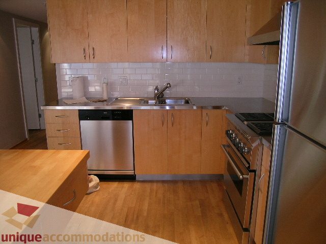 Bright kitchen with light wood cabinets, stainless steel appliances, and hardwood floors. - 402-1155 Mainland St, Vancouver Downtown