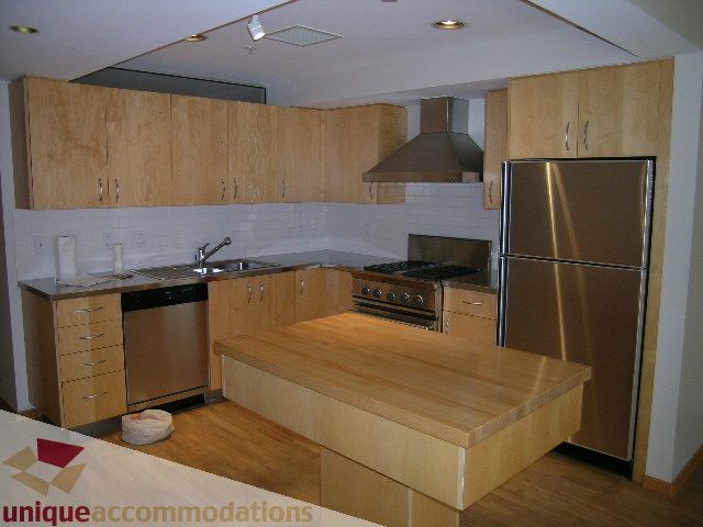 Bright kitchen with light wood cabinets, stainless steel appliances, and a large island. - 402-1155 Mainland St, Vancouver Downtown