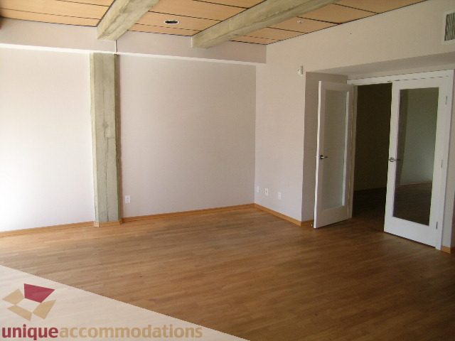 Open living space with hardwood floors and exposed beams. - 402-1155 Mainland St, Vancouver Downtown