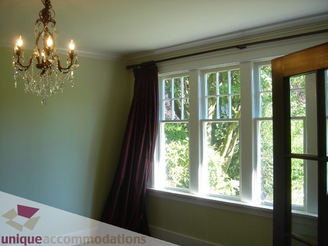 Bright living room with large windows, green walls, and elegant chandelier. - 1475 W 33rd Ave, Vancouver West Side