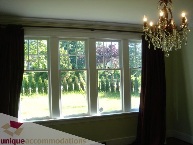 Bright living room with large bay windows, green walls, and elegant chandelier. - 1475 W 33rd Ave, Vancouver West Side