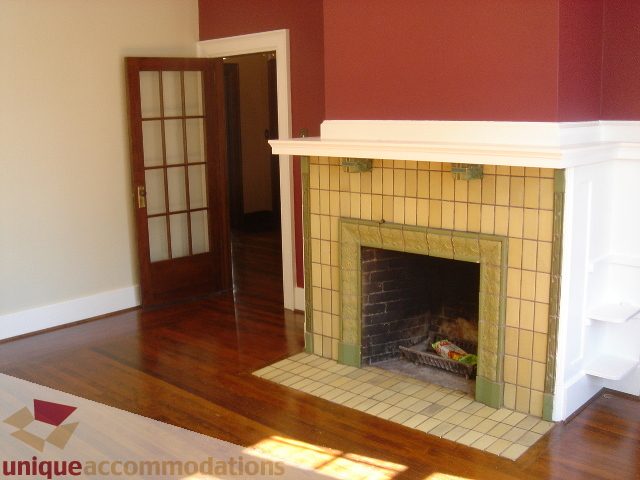 Bright living room with hardwood floors and a tiled fireplace, leading to another room. - 1475 W 33rd Ave, Vancouver West Side