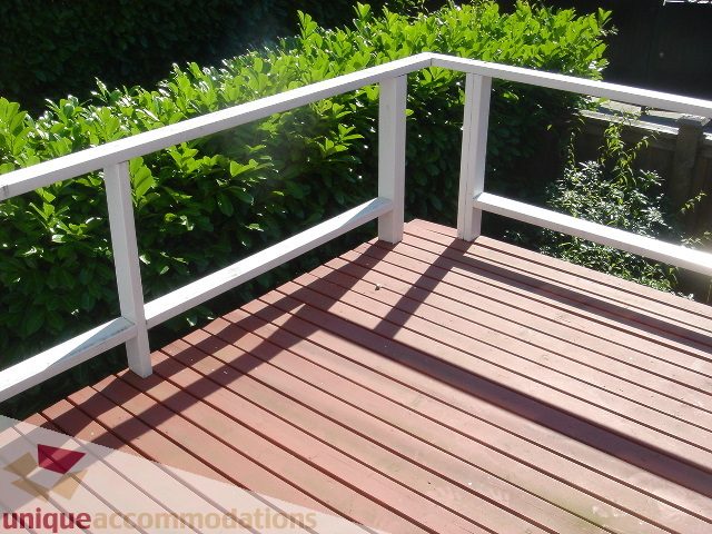 Bright deck with wooden flooring and white railings, surrounded by greenery. - 1475 W 33rd Ave, Vancouver West Side