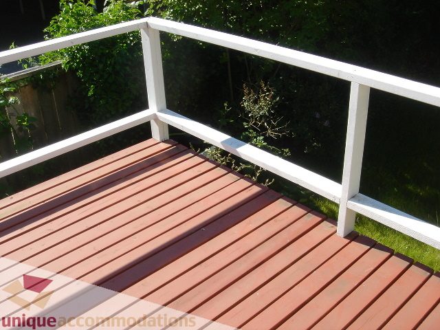 Furnished balcony with wooden deck and white railing, overlooking greenery. - 1475 W 33rd Ave, Vancouver West Side