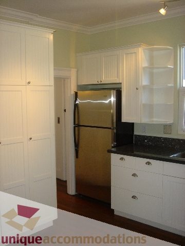 Bright kitchen with white cabinets, black countertops, and hardwood floors. - 1475 W 33rd Ave, Vancouver West Side