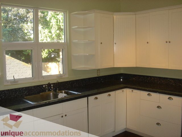 Bright kitchen with white cabinets, black countertops, and a large window. - 1475 W 33rd Ave, Vancouver West Side