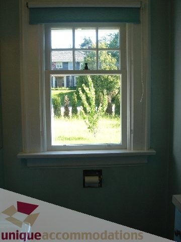 Bright living room with large window, greenery outside, cozy ambiance. - 1475 W 33rd Ave, Vancouver West Side