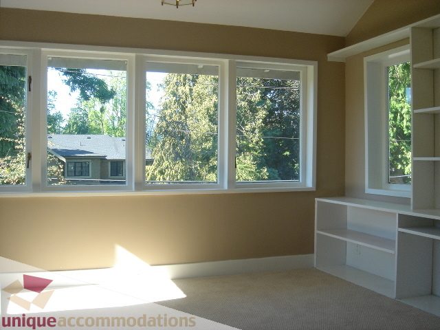 Bright living room with large windows and built-in shelving, offering a city view. - 1475 W 33rd Ave, Vancouver West Side