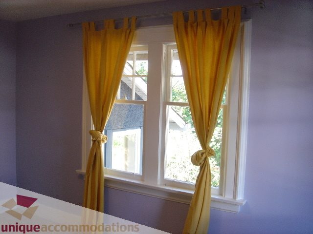 Bright living room with large windows and yellow curtains. - 1475 W 33rd Ave, Vancouver West Side