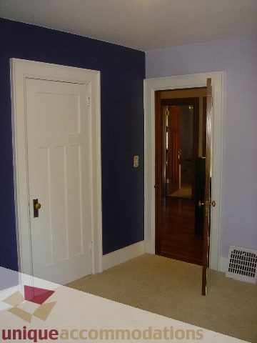Bright hallway leading to a 5-bedroom house, featuring a dark blue accent wall and a wooden door. - 1475 W 33rd Ave, Vancouver West Side