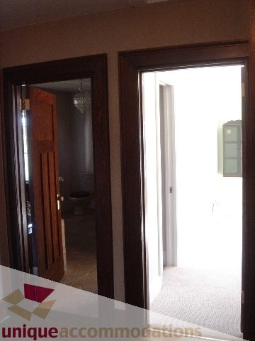 Bright hallway leading to a well-lit room with wooden doors and a chandelier. - 1475 W 33rd Ave, Vancouver West Side