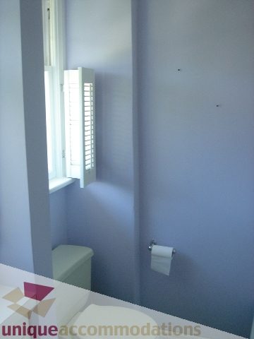 Bathroom with toilet and toilet paper holder, white shutters on window. - 1475 W 33rd Ave, Vancouver West Side