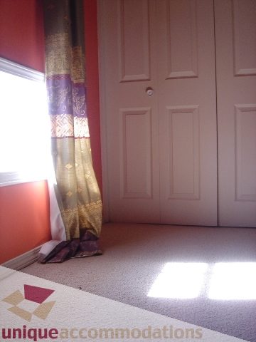 Bright bedroom with red walls and patterned curtains, natural light streaming in. - 1475 W 33rd Ave, Vancouver West Side