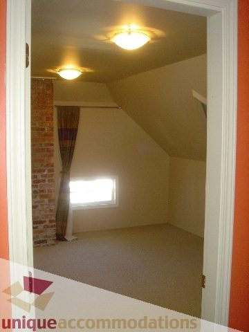 Bright bedroom with sloped ceiling and orange accent wall. - 1475 W 33rd Ave, Vancouver West Side