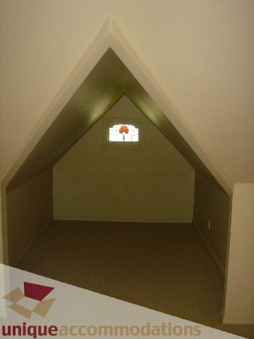 Attic space with sloped ceiling and small window. - 1475 W 33rd Ave, Vancouver West Side