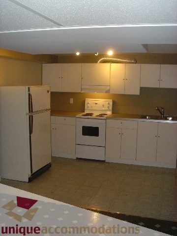 Bright kitchen with white cabinets, stainless steel appliances, and beige countertops. - 1475 W 33rd Ave, Vancouver West Side