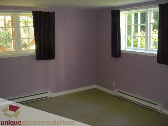 Bright living room with purple walls and large windows, carpeted floor. - 1475 W 33rd Ave, Vancouver West Side
