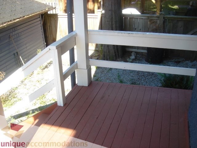 Furnished deck with red wood planks and white railings, surrounded by greenery. - 1475 W 33rd Ave, Vancouver West Side