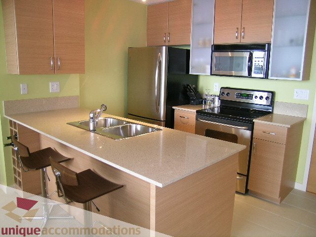 Bright kitchen with light wood cabinets, granite countertops, and stainless steel appliances. - 2707 - 928 Homer Street, Vancouver Downtown