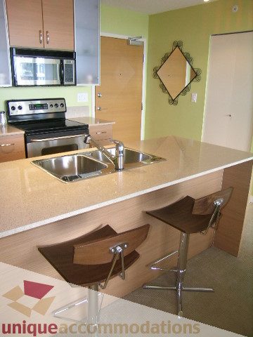 Bright kitchen with granite countertops and modern bar stools, showcasing a cozy and functional space. - 2707 - 928 Homer Street, Vancouver Downtown