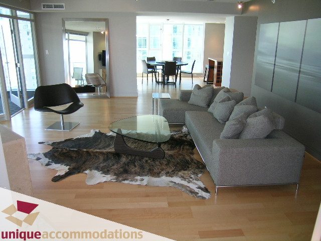 Furnished living room with hardwood floors, cowhide rug, and city view. - 1603-1650 Bayshore Drive, Vancouver Downtown